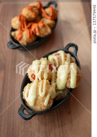 Crispy bites with creamy sauce and vibrant drizzle on a wooden table 137579448