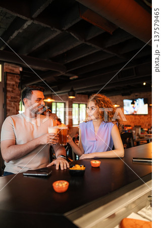 Couple toasting with beer glasses at the counter in a pub 137579465