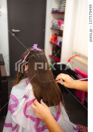 Child girl getting a professional haircut in hair salon Child girl getting a professional haircut in hair salon 137579499