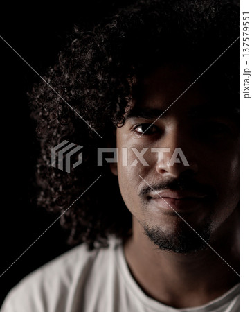 Young african-american man with curly hair posing in the shadows Young african-american man with curly hair posing in the shadows 137579551