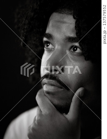 Pensive young african-american man with hand on chin looking up thoughtfully 137579552