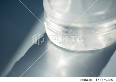 水滴がついた清涼感のある冷たいミネラルウォーターのペットボトルの下部と透過光 137579880