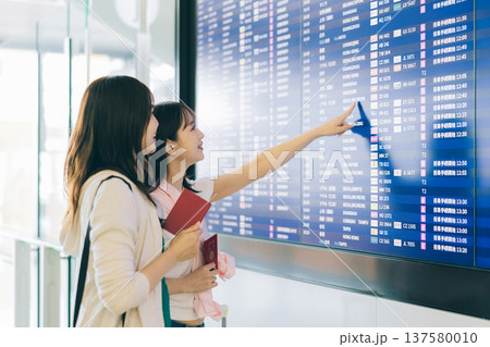 空港の電光掲示板を見る女性2人組　「撮影協力：関西国際空港（KIX）」 137580010
