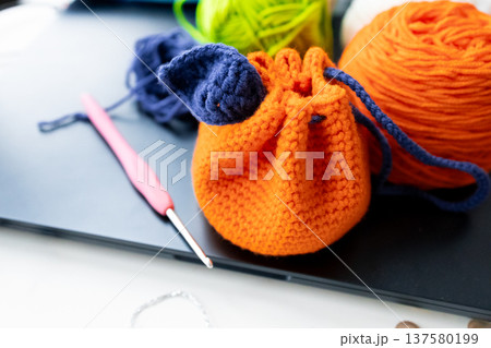 Colorful crochet project with orange bag, yarn balls, and hook on table Colorful crochet project with orange bag, yarn balls, and hook on table 137580199