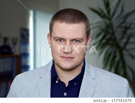 Confident young businessman in casual gray blazer and blue shirt, successful entrepreneur office portrait, male professional looking at camera, headshot Confident young businessman in casual gray blazer and blue shirt, successful entrepreneur office portrait, male professional looking at camera, headshot 137581070