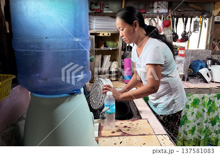 Middle-aged Filipino woman washing kitchen utensils in authentic rustic home kitchen, Asian lady doing domestic chores, daily life routine portrait Middle-aged Filipino woman washing kitchen utensils in authentic rustic home kitchen, Asian lady doing domestic chores, daily life routine portrait 137581083
