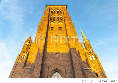 St. Mary's Church in Gdansk, a city on the Baltic coast of northern Poland, Europe. Towering brick architecture reaches for the heavens against a clear blue sky. St. Mary's Church in Gdansk, a city on the Baltic coast of northern Poland, Europe. Towering brick architecture reaches for the heavens against a clear blue sky. 137581182