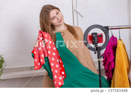 Fashion influencer showcasing clothing on a live stream in a bright setting Fashion influencer showcasing clothing on a live stream in a bright setting 137581486