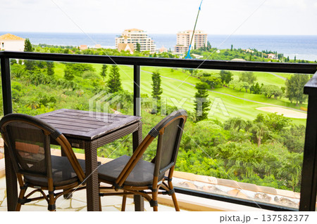 ホテルテラスのテーブルとイスから眺めるゴルフ場と海、南国リゾートの風景（沖縄県宮古島市） 137582377