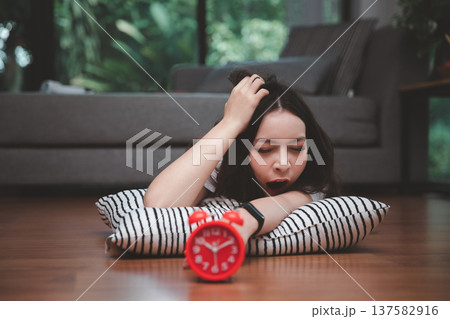 Young asian woman reaching over to turning off alarm clock while lying on the floor in living room at home. Young asian woman reaching over to turning off alarm clock while lying on the floor in living room at home. 137582916