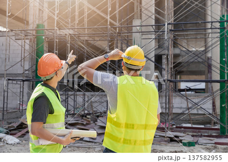 Confident team of architect working together in building construction site. They discussing about new startup project. Architect discuss with engineer about project . Architectural concept. 137582955