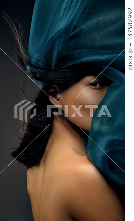 Korean woman framed by moving teal silk fabric expressing freedom, elegance and luxury. Korean woman framed by moving teal silk fabric expressing freedom, elegance and luxury. 137582992
