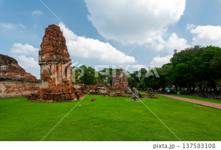 Ancient stupa towers in Ayutthaya historical park, Thailand. Ruins of former Siam capital under blue sky on sunny day. Famous travel destination with cultural heritage and Buddhist history. 137583108