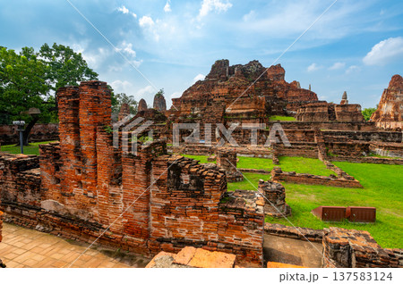 Ancient stupa towers in Ayutthaya historical park, Thailand. Ruins of former Siam capital under blue sky on sunny day. Famous travel destination with cultural heritage and Buddhist history. 137583124