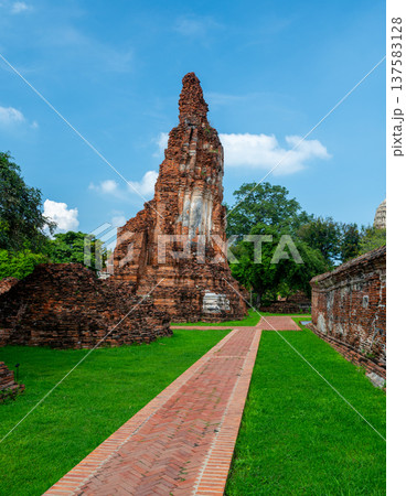 Ancient stupa towers in Ayutthaya historical park, Thailand. Ruins of former Siam capital under blue sky on sunny day. Famous travel destination with cultural heritage and Buddhist history. 137583128
