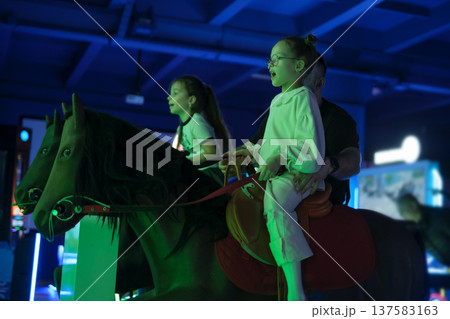 Kids and dad ride an interactive horse in an amusement park 137583163