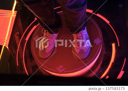 A glowing neon button for an outdoor dance game with arrows in an amusement park. Guy on Dance Pad, Retro Gaming Icon A glowing neon button for an outdoor dance game with arrows in an amusement park. Guy on Dance Pad, Retro Gaming Icon 137583173