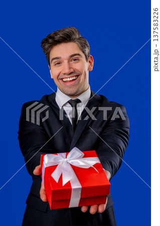Handsome Businessman In Suit Gives Gift Box Present To Camera. Mature man smiles Handsome Businessman In Suit Gives Gift Box Present To Camera. Mature man smiles 137583226