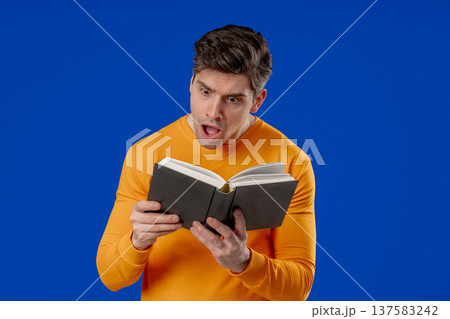 Surprised Man Reading Book With Shocked Expression. Education, learning, knowledge, literature Surprised Man Reading Book With Shocked Expression. Education, learning, knowledge, literature 137583242