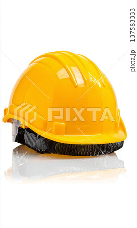 A hard hat is placed on a flat surface, showing its bright yellow color. This hard hat is used for safety at construction sites to protect workers' heads from hazards 137583333
