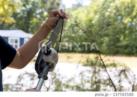 Working with chainsaw to trim branches in yard in suburban area Working with chainsaw to trim branches in yard in suburban area 137583580