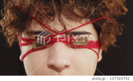 The teenager's face is entwined with red thread. Psychology. The problems of adolescence. Youthful maximalism The teenager's face is entwined with red thread. Psychology. The problems of adolescence. Youthful maximalism 137583742