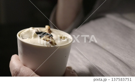 A creamy dessert with nuts and prunes in hand on his stomach. 137583751
