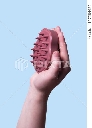 Hair pink scalp massager in woman hand on the pink background isolated. Image with copy space. Mock up for design and banner. Vertical Hair pink scalp massager in woman hand on the pink background isolated. Image with copy space. Mock up for design and banner. Vertical 137584422