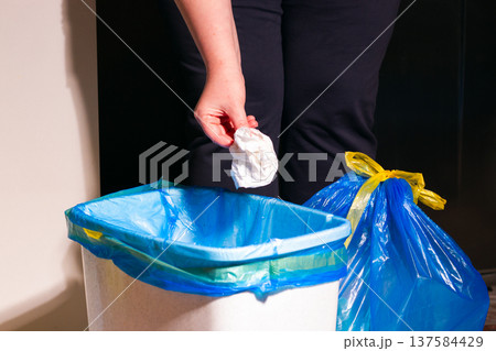 Woman throwing garbage into trash bin in kitchen Woman throwing garbage into trash bin in kitchen 137584429