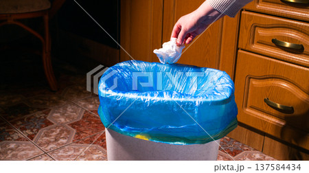 Woman throwing garbage into trash bin in kitchen 137584434