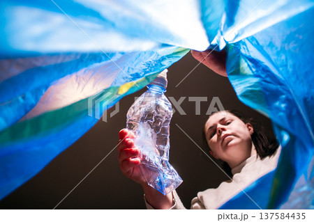Woman throwing garbage into blue trash bag. Low angle. Look from inside of bag 137584435