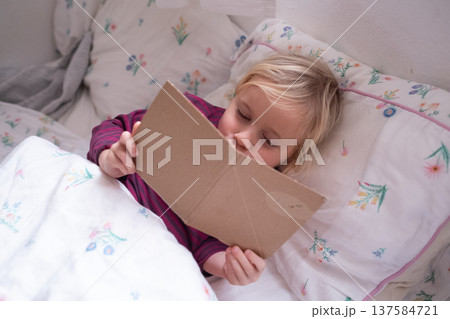 Little 4 Year Old Girl Reading Her Handmade Book in Bed Little 4 Year Old Girl Reading Her Handmade Book in Bed 137584721