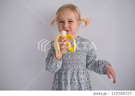 Little 4 Year Old Girl Eating Banana on White Background 137584727