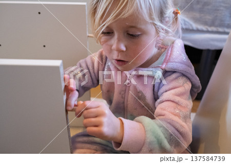 Independent 4 year old girl assembling furniture with a screwdriver in a modern home interior Independent 4 year old girl assembling furniture with a screwdriver in a modern home interior 137584739