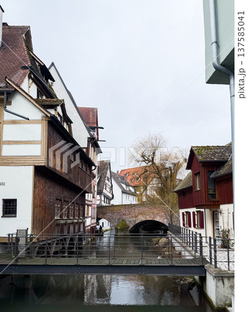 A tranquil canal in the fishermans quarter of Ulm, Germany. Reflections of colorful buildings line the waters edge, creating a serene urban scene. A tranquil canal in the fishermans quarter of Ulm, Germany. Reflections of colorful buildings line the waters edge, creating a serene urban scene. 137585041