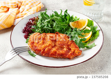 Milanese chicken, Crispy breaded chicken served, with fresh herbs, and lemon wedges, 137585208