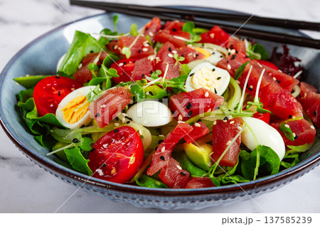 salad with fresh tuna, cherry tomatoes and quail eggs and avacado, served with chopsticks, 137585239