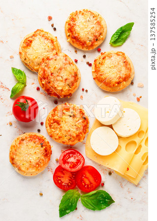Freshly baked mini pizza on a marble table, with fresh vegetables and cheese, top view, 137585254