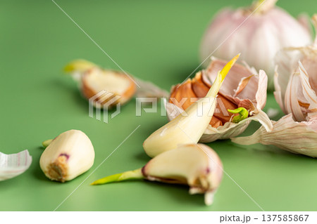 fresh garlic cloves with peel on green background fresh garlic cloves with peel on green background 137585867