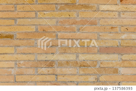 Photograph of a yellow-beige brick wall, front view 137586393