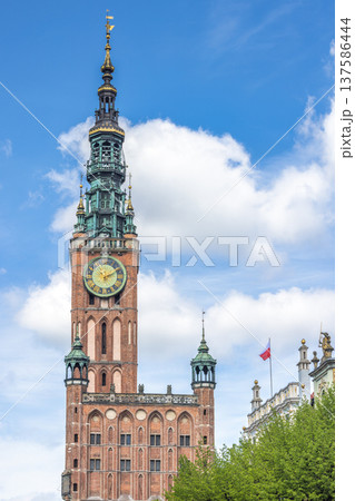 The Main Town Hall in Gdansk, a city on the Baltic coast of northern Poland, Europe. Historic clock tower rises against a cloudy blue sky, showcasing intricate architecture. 137586444