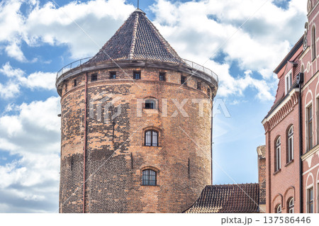 Gdansk, a city on the Baltic coast of northern Poland, Europe. Historic brick tower stands tall against a bright, cloudy sky, showcasing architectural details of a building from a bygone era. Gdansk, a city on the Baltic coast of northern Poland, Europe. Historic brick tower stands tall against a bright, cloudy sky, showcasing architectural details of a building from a bygone era. 137586446