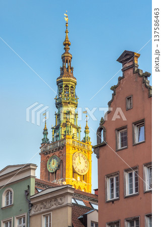 Gdansk, a city on the Baltic coast of northern Poland, Europe. Historical architecture is showcased in this view of a clock tower rising above colorful buildings against a clear blue sky backdrop. 137586463