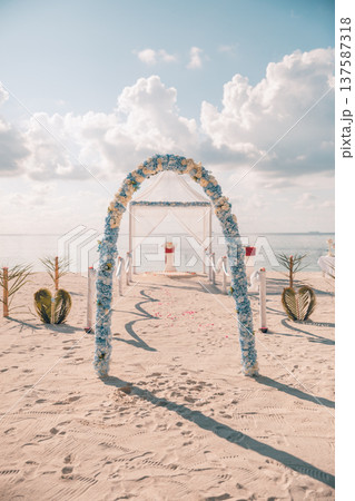 Romantic sunset beach wedding arch decorated flowers sandy shore radiant ocean horizon love couple tropical destination ceremony 137587318
