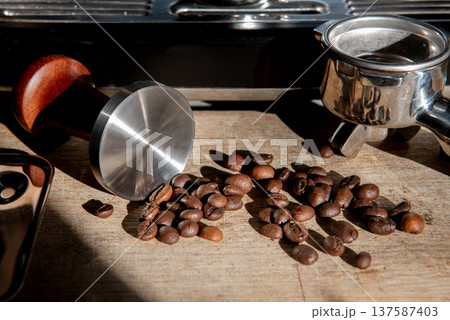 espresso machine with coffee beans and tamper in warm sunlight espresso machine with coffee beans and tamper in warm sunlight 137587403