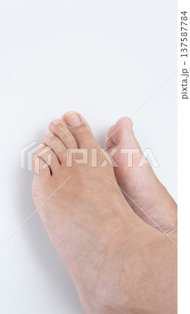 Close-up view of two bare feet resting on a clean white surface, showcasing natural skin texture and relaxed positioning in a serene environment Close-up view of two bare feet resting on a clean white surface, showcasing natural skin texture and relaxed positioning in a serene environment 137587784