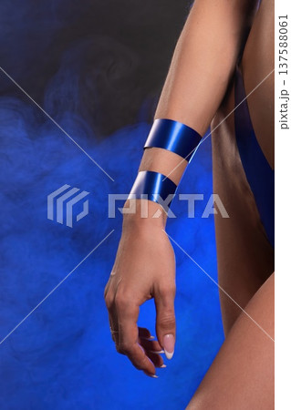 Model shows blue tape on arm while posing in studio with blue background and smoke effects 137588061