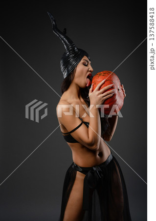 Woman in avant-garde costume with pumpkin under artistic light projection 137588418