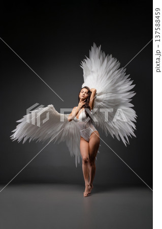 Woman with angelic wings posing gracefully under soft light projection 137588459