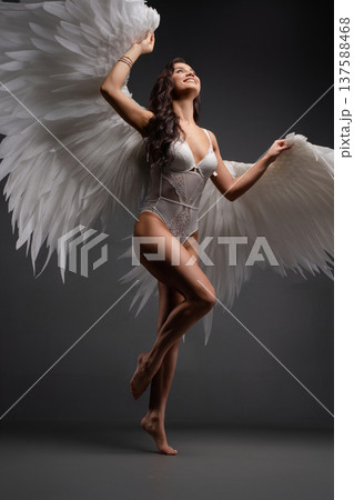 Woman with angel wings poses gracefully under colorful light projection 137588468
